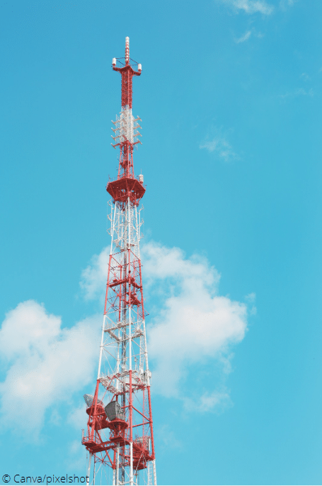 Ein rot-weißer Funkmast vor einem blauen Himmel mit ein paar Wolken.